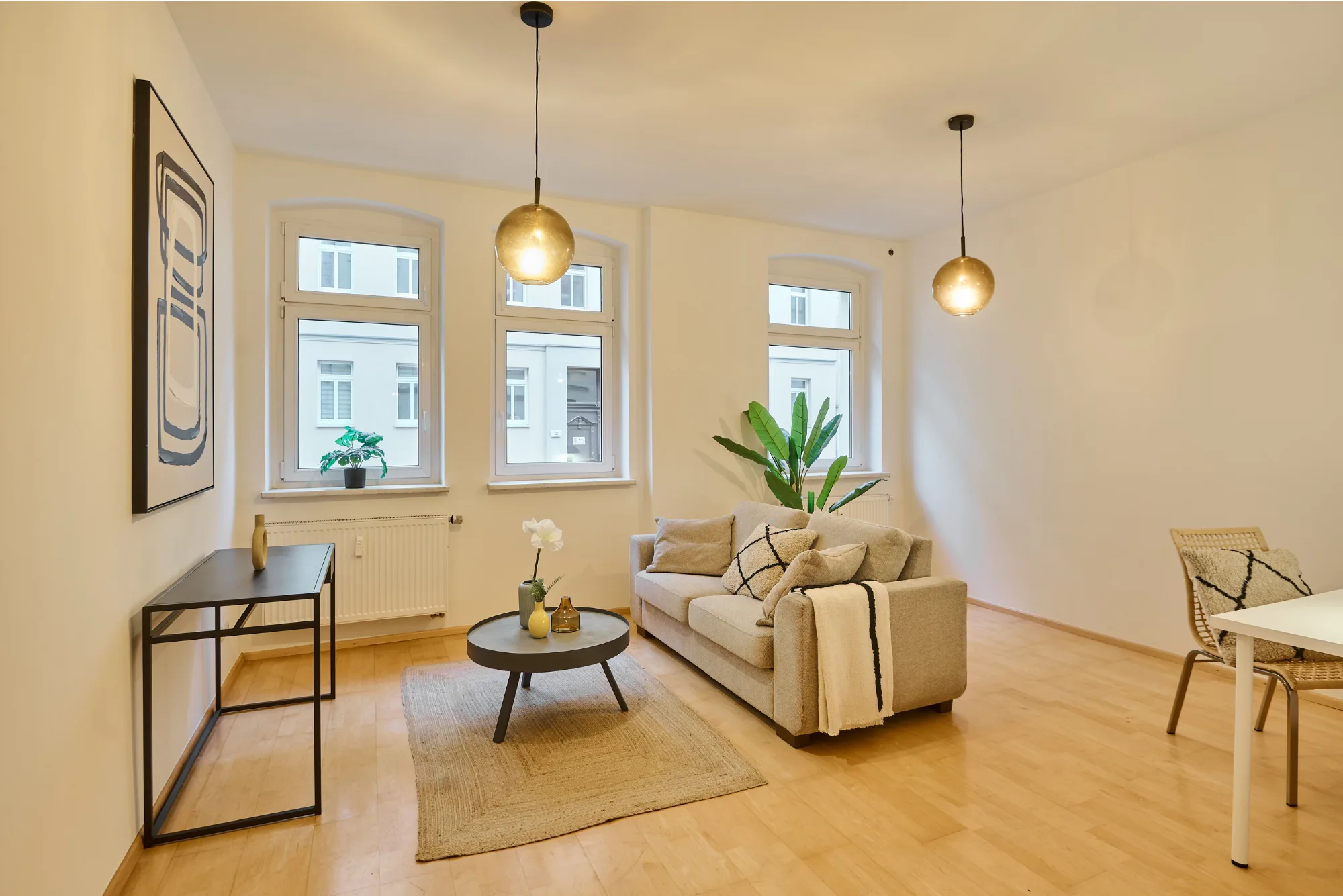 Blick in ein gestautes Wohnzimmer mit hellem Sofa, und hochwertigen Details in schwarz