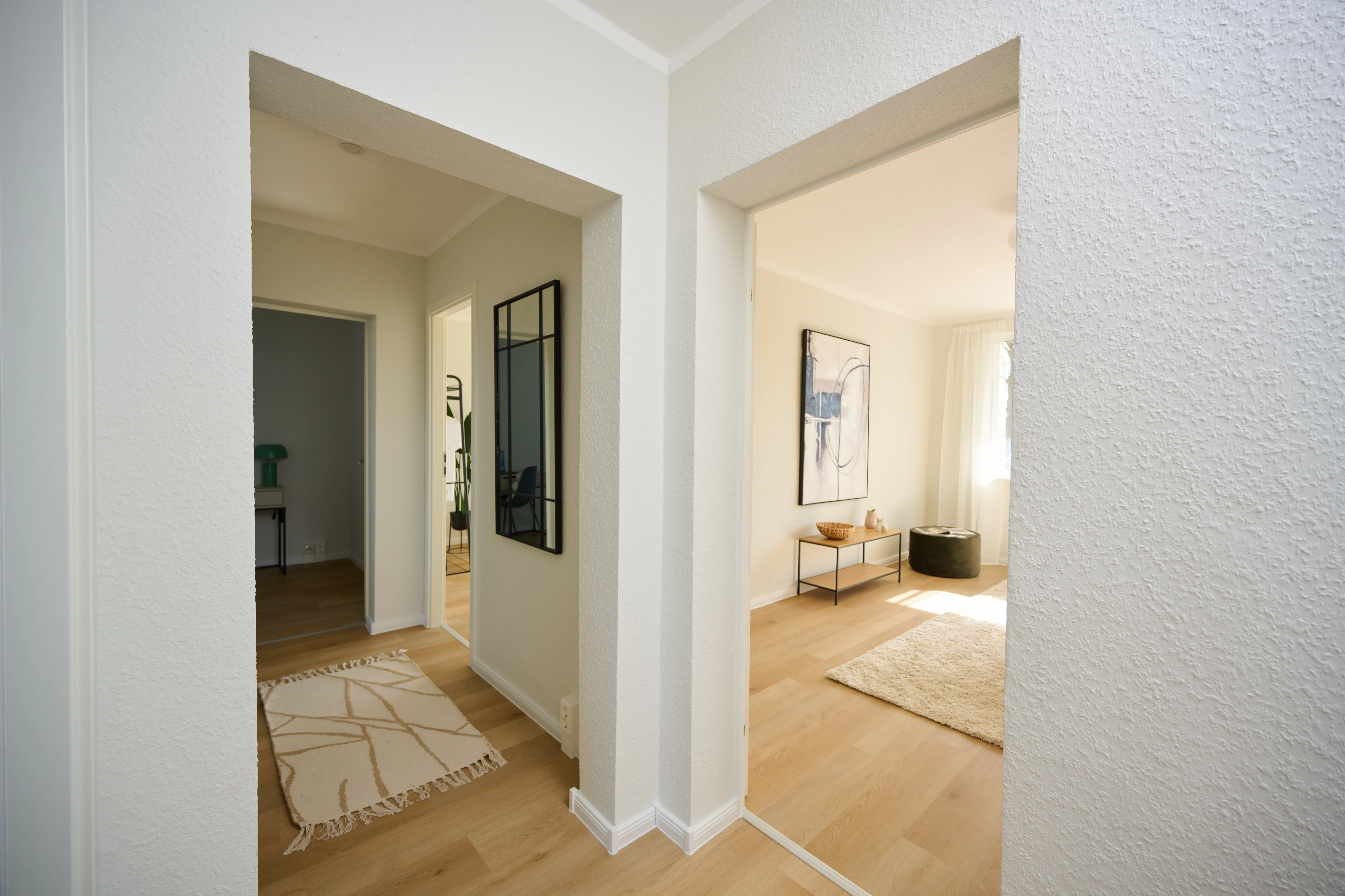 Blick in eine Musterwohnung vom Flur in das Wohnzimmer, helle Gestaltung